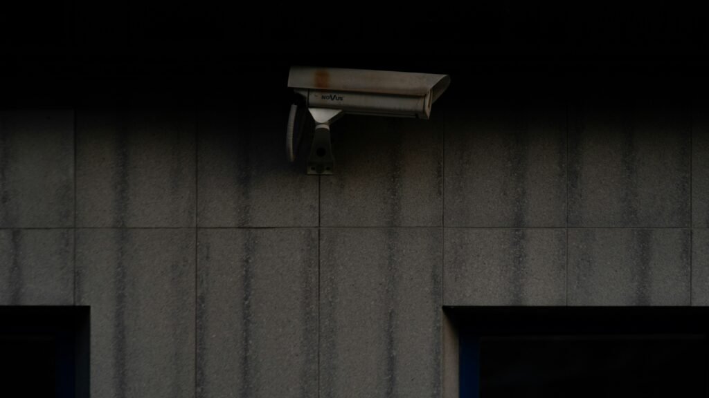 Two white, modern security cameras mounted on a building facade with contrasting black and white stripes, symbolizing dual-perspective CCTV monitoring coverage.